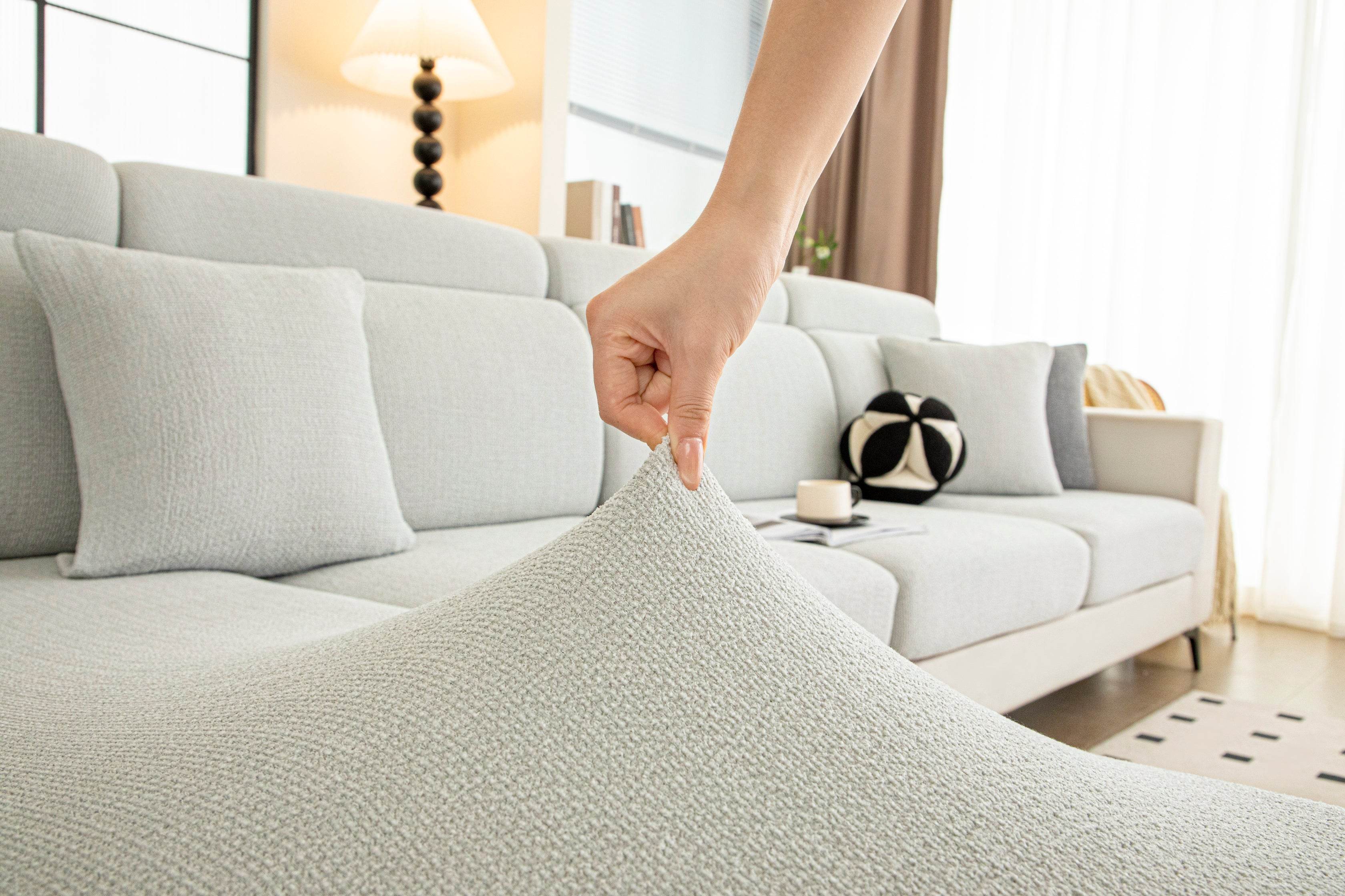 Close-up of the Cozee Chenluxe Sofa Cover fabric being pinched, showing thick plush chenille softness, skin-friendly feel, and durable weave.