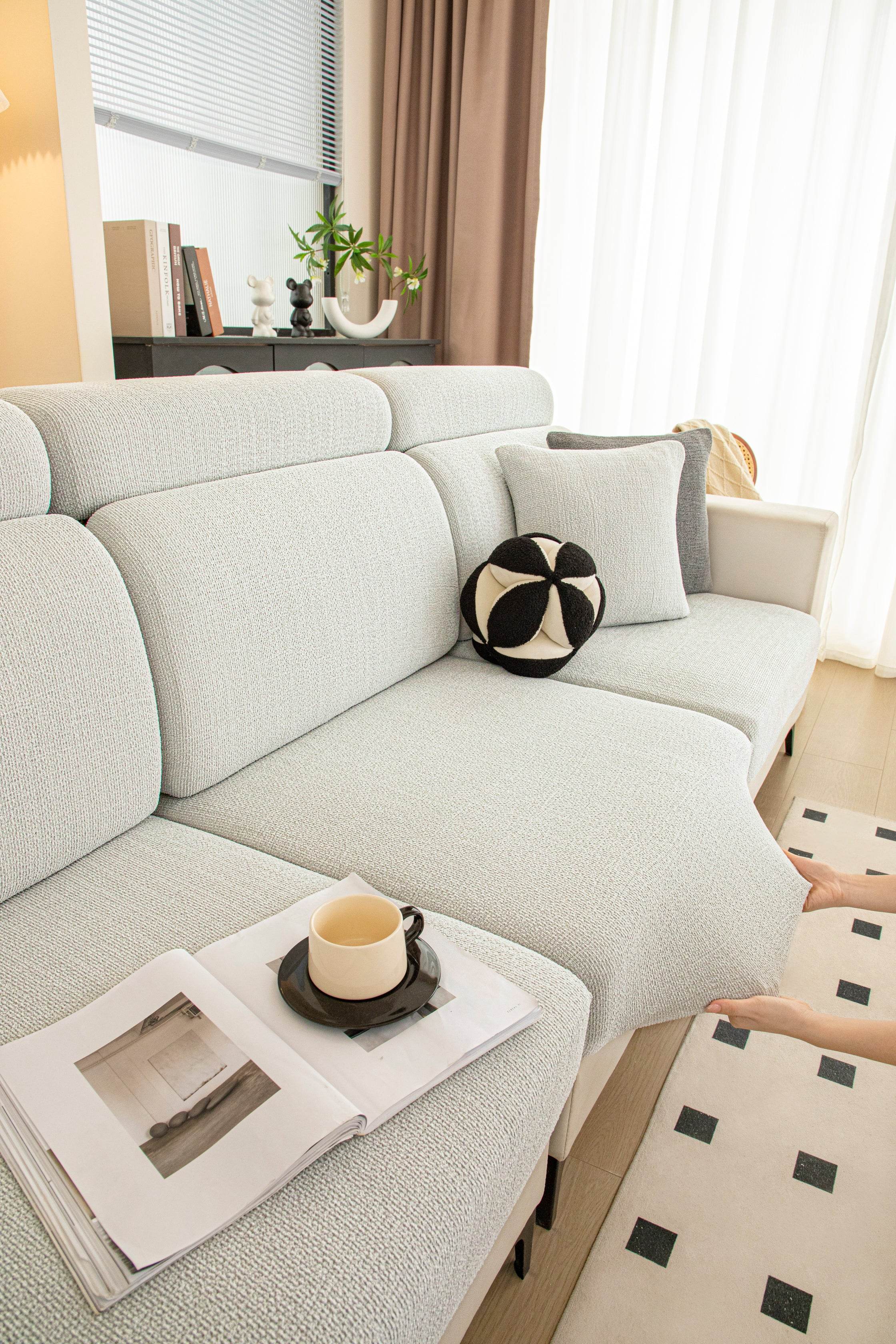 Corner of the Cozee Chenluxe Sofa Cover being stretched, demonstrating fabric flexibility, snug fit, and durable full coverage.