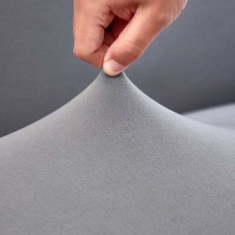 Close-up of a hand pulling the Cozee Comfort Guard Slipcover fabric, highlighting its textured surface, flexible stretch, and rich color for a protective and stylish fit