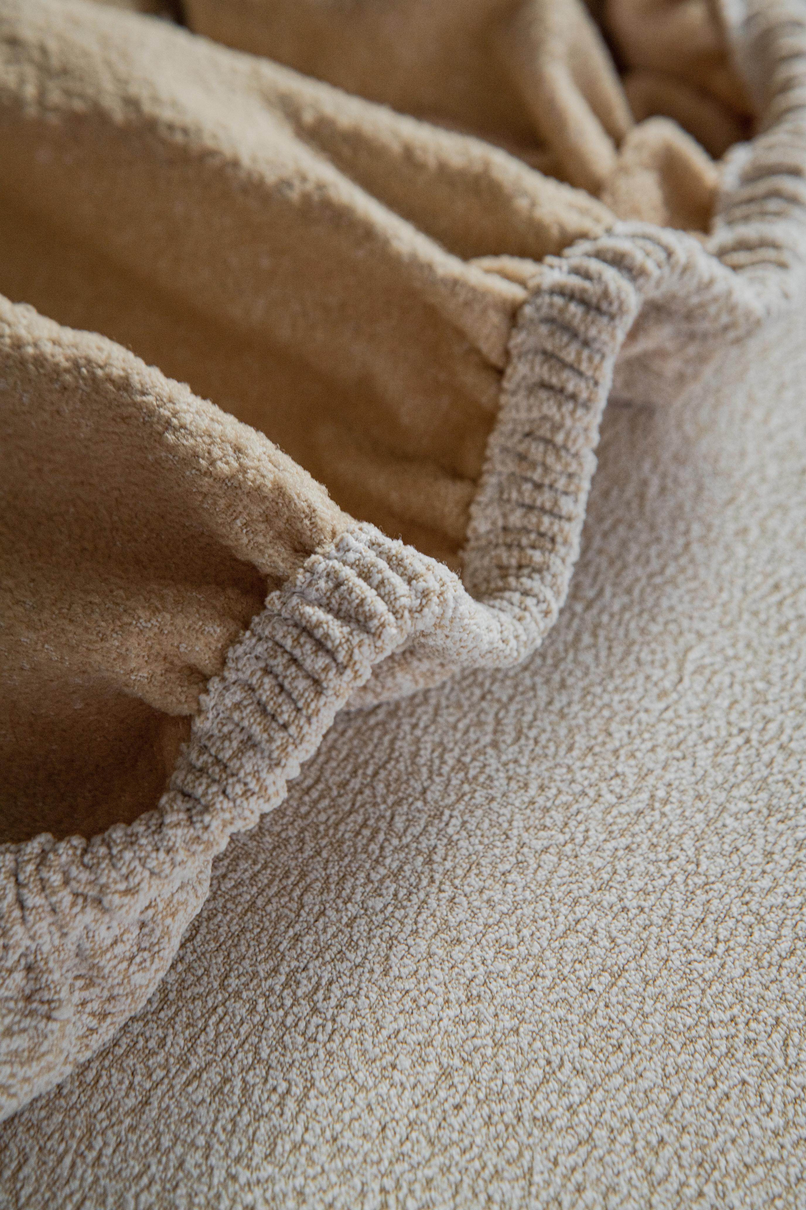 Close-up of the Cozee Cozura Sofa Cover showing stretchy reinforced seams, highlighting durable stitching and a snug flexible fit.