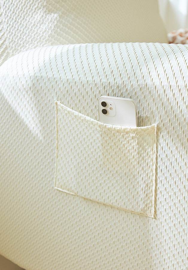 Close-up of built-in side pocket on EverPlush slipcover holding a smartphone, showing convenient storage for remotes, devices, or small essentials