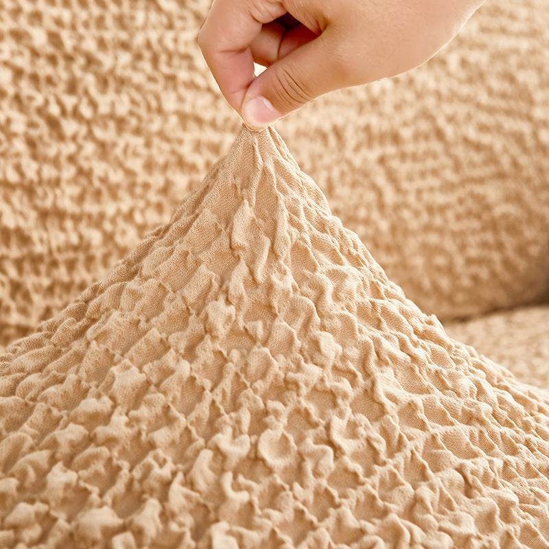 Close-up of hand pinching the Cozee Microfiber Slipcover to show soft-touch, lightweight polyester fabric with gentle stretch and smooth texture