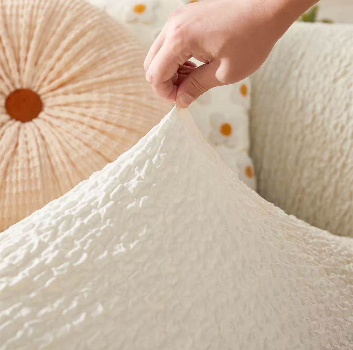 Close-up of hand pinching the Cozee Microfiber Slipcover to show soft-touch, lightweight polyester fabric with gentle stretch and smooth texture