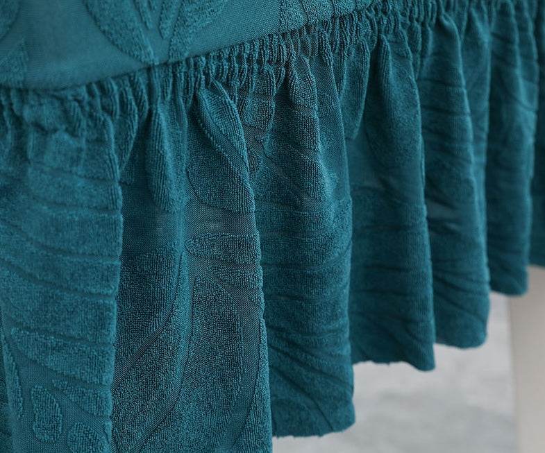 Close-up of teal fabric with a textured, patterned design, highlighting the elegant weave and decorative detail of the Cozee SoftWeave Skirted Chair Cover