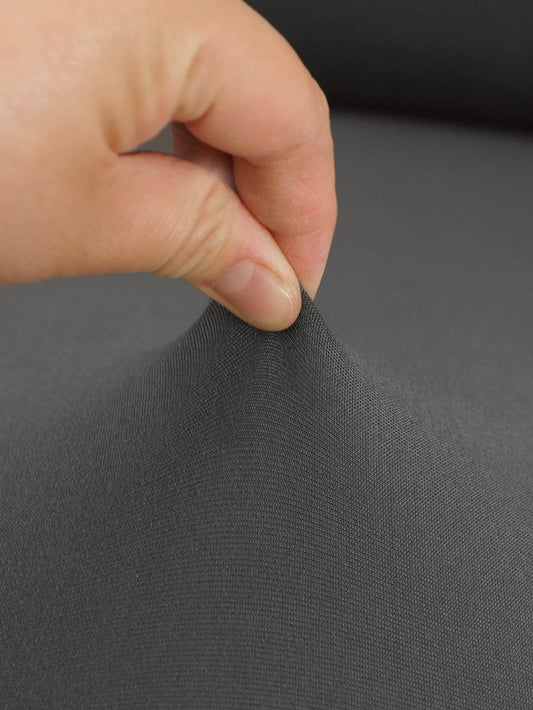 Close-up of hand pinching soft, stretchy chair cover fabric, showing the flexibility and smooth texture of the Cozee Stretch Fit Chair Cover for a snug, wrinkle-free fit