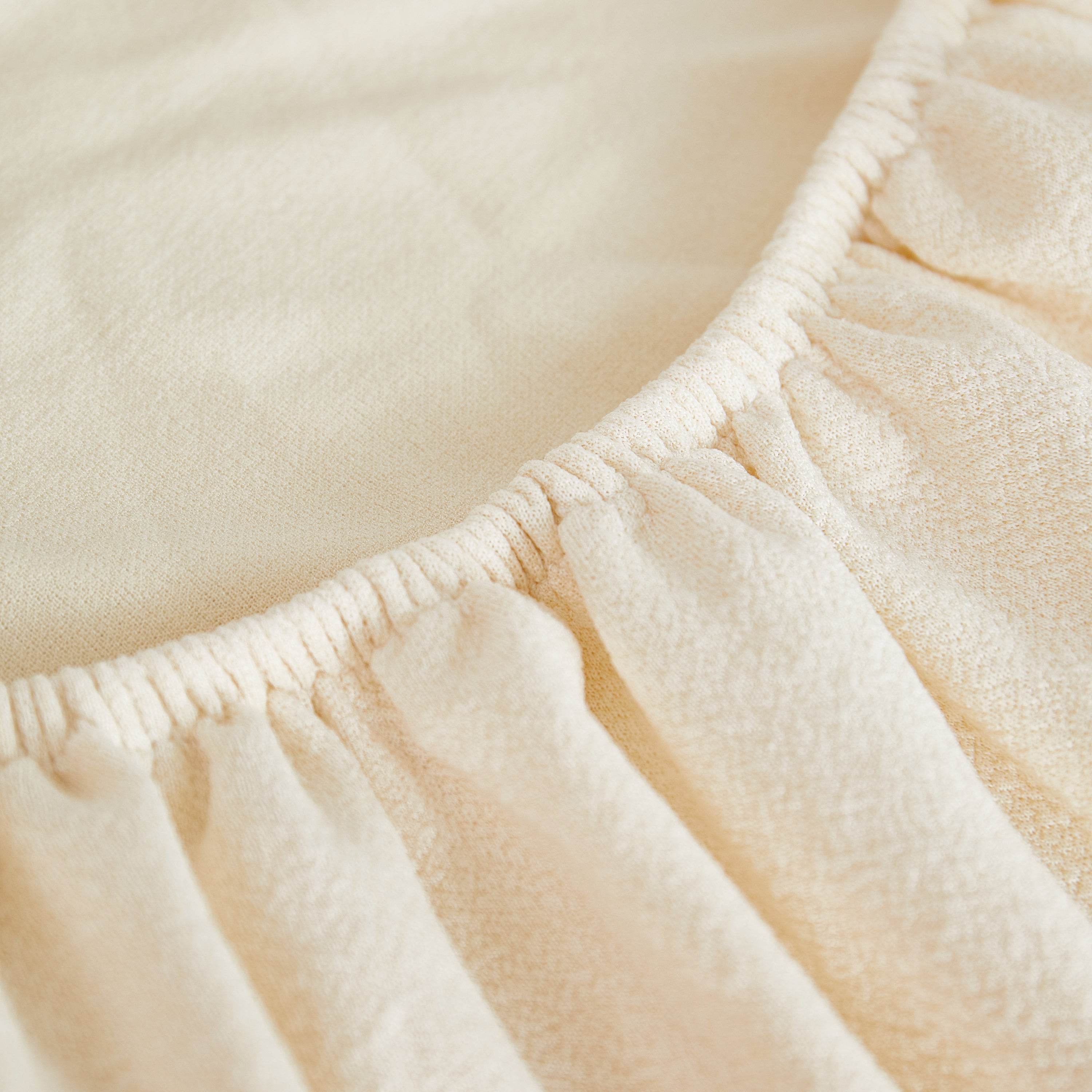 Close-up of cream teddy fleece fabric with a soft texture and visible seam edge—highlighting premium stitching in cozy couch and sofa covers.