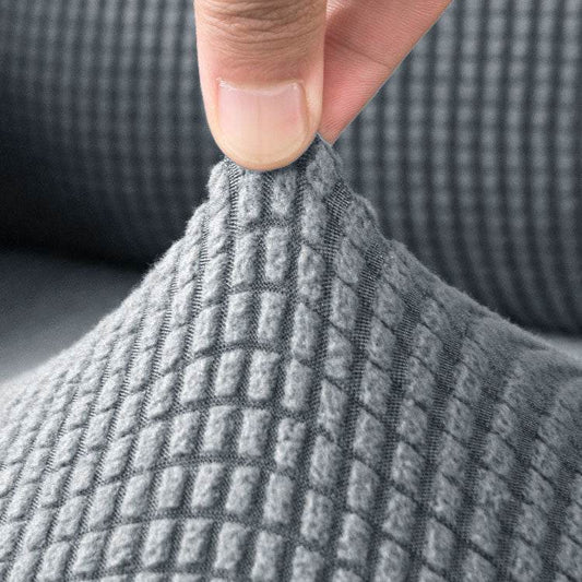 Close-up of a hand holding the textured fleece fabric of the Cozee Timeless Arm Cover, showcasing its soft, plush feel and stretchable quality for snug, secure coverage