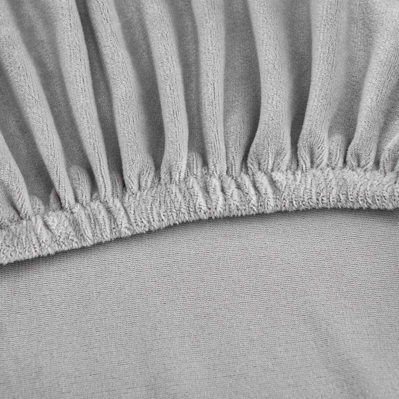 Close-up of gray fitted slipcover with pleated edge, showing the neat finish and tailored fit of the Cozee Ultra Soft Plush Chair Cover