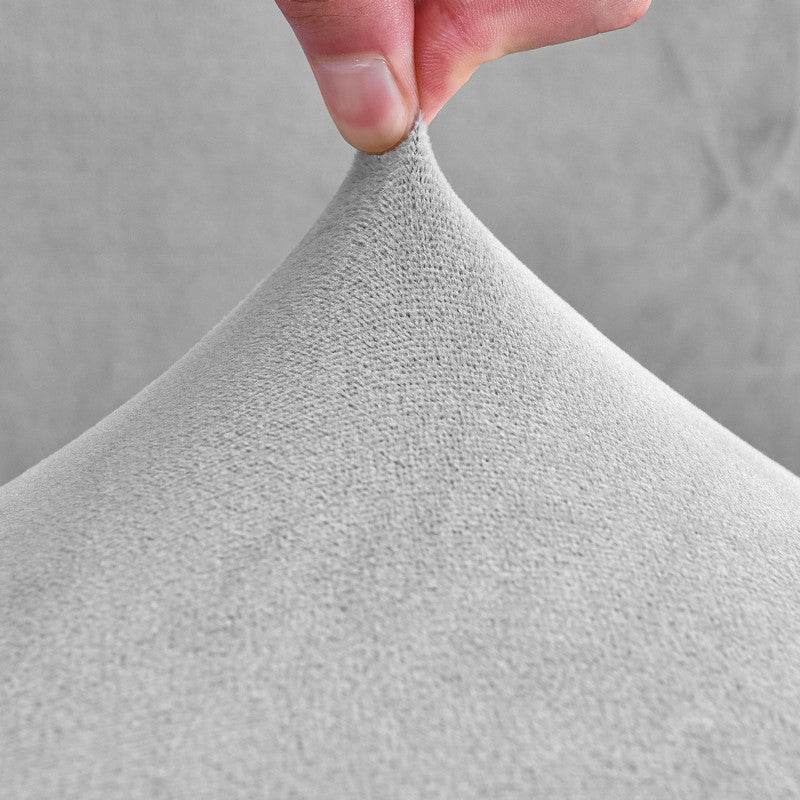 Close-up of a hand holding textured gray fabric against a neutral background, highlighting the weave, softness, and quality of the Cozee Ultra Soft Plush Chair Cover material
