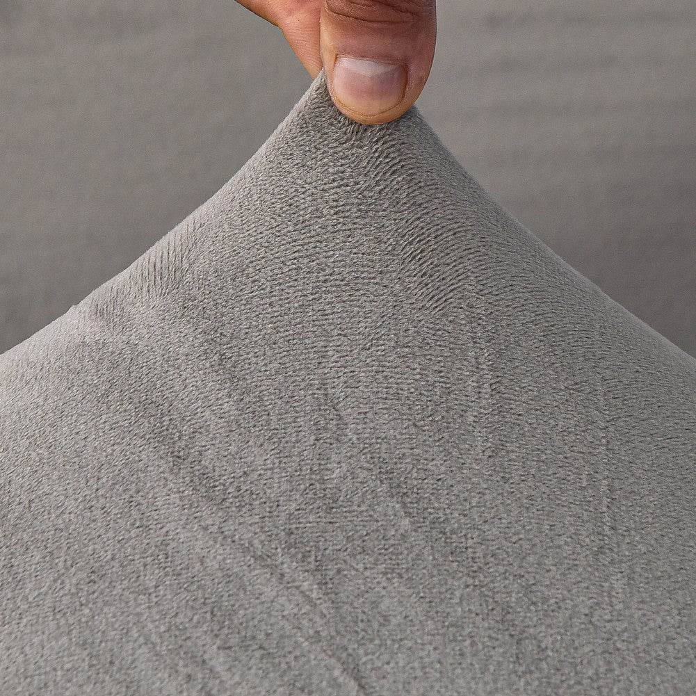 Close-up of plush sofa cover fabric with a hand lifting the corner, highlighting the soft texture, stretchability, and easy handling of the Cozee Ultra Soft Plush Slipcover