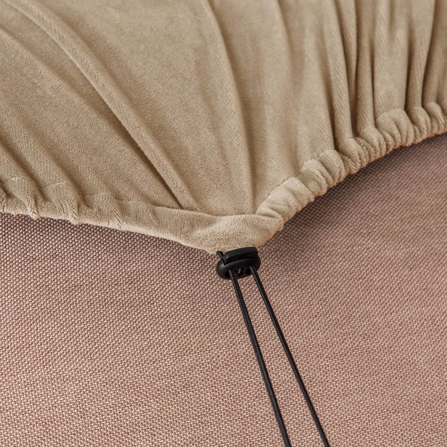 Close-up of beige velvet slipcover fabric with a black elastic drawstring, showing adjustable fit feature for a secure and custom stretch cover