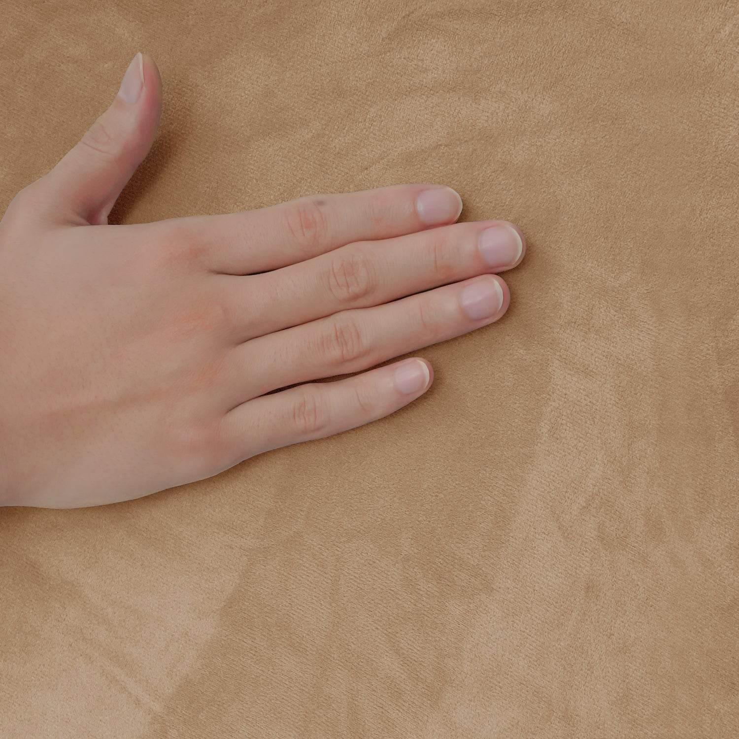 Close-up of a hand resting on brown textured velvet slipcover, highlighting the soft-touch feel and rich surface detail of the Cozee Stretch Slipcover