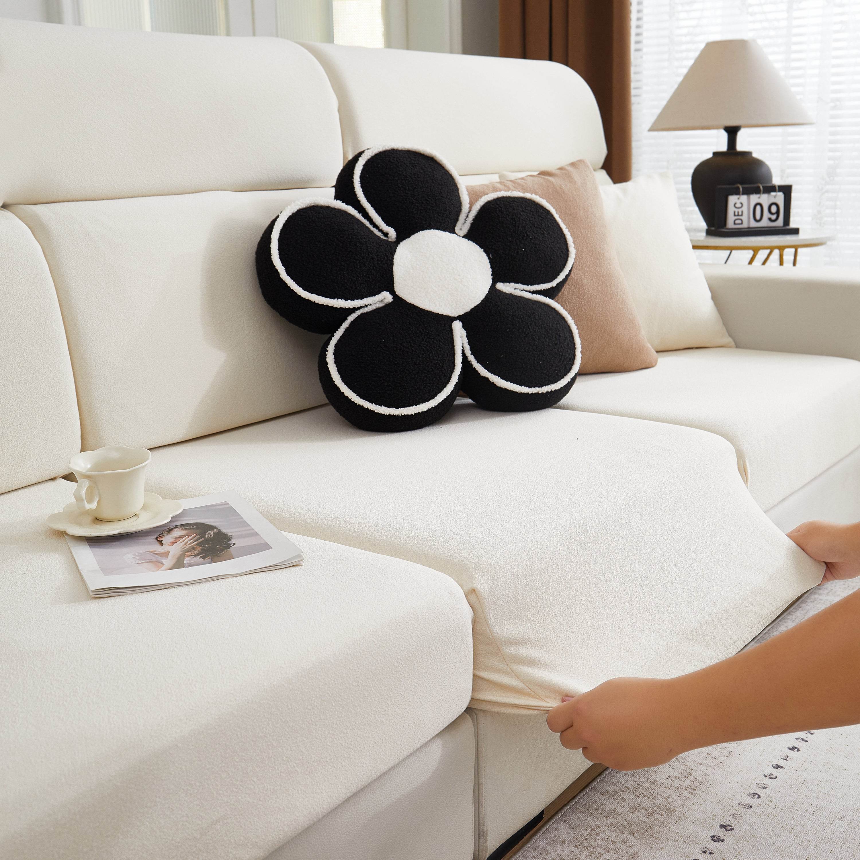 Close-up of a hand adjusting the corner of a sofa covered with a stretch-fit couch cover, showing snug fit and easy installation.
